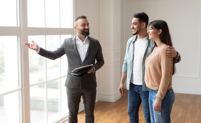 Three people standing in front of a window in a new home.