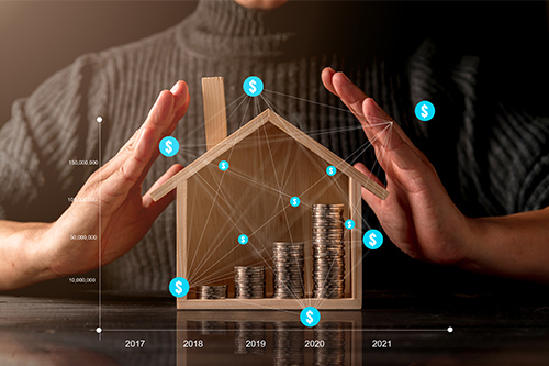 A man holding a house with coins in his hands.