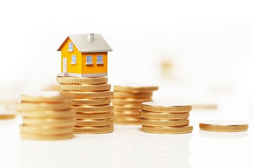 A small house on top of stacks of gold coins.