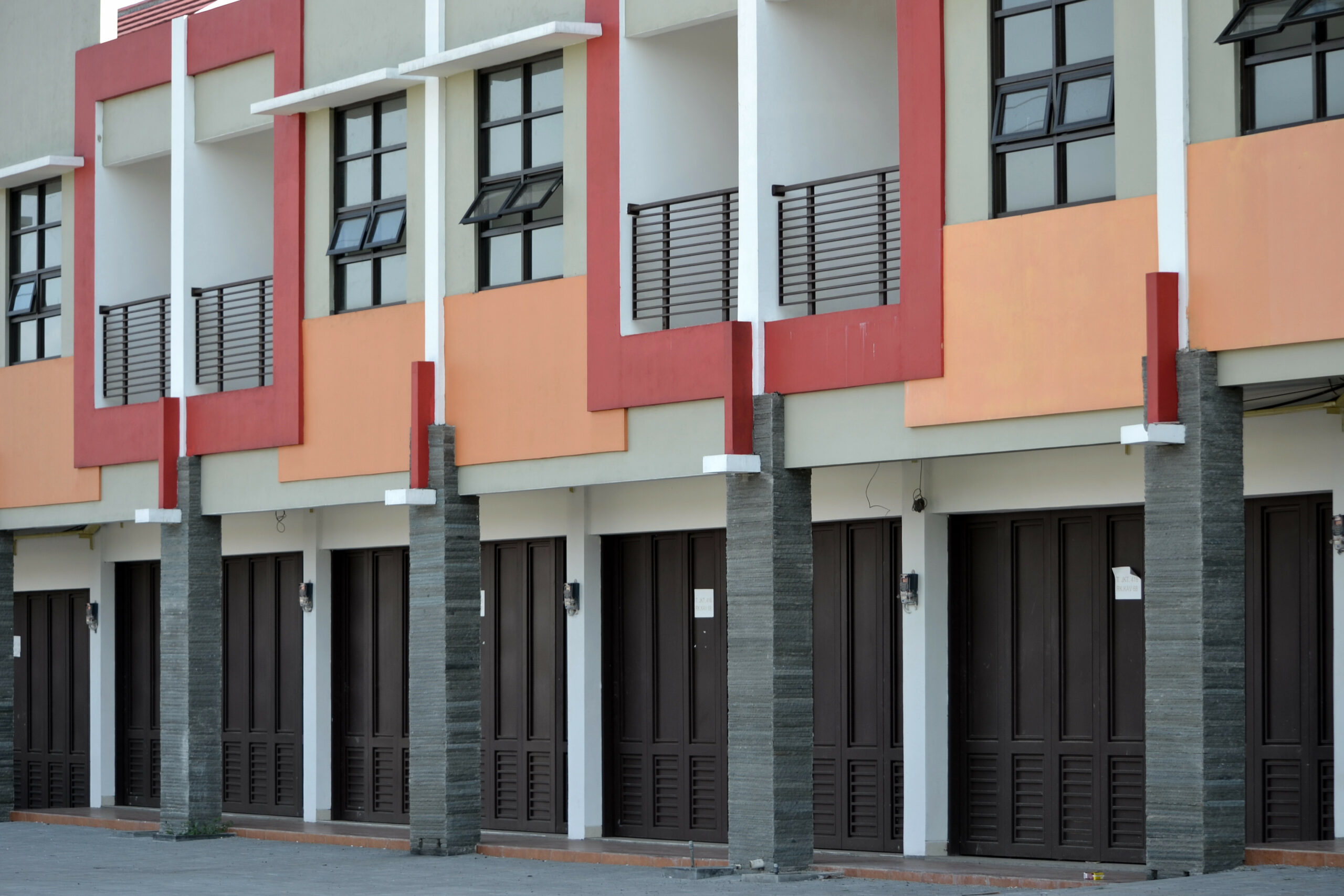 A row of apartment buildings with doors and windows.