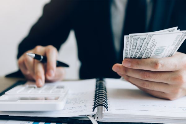 A man in a suit is holding money and a calculator.