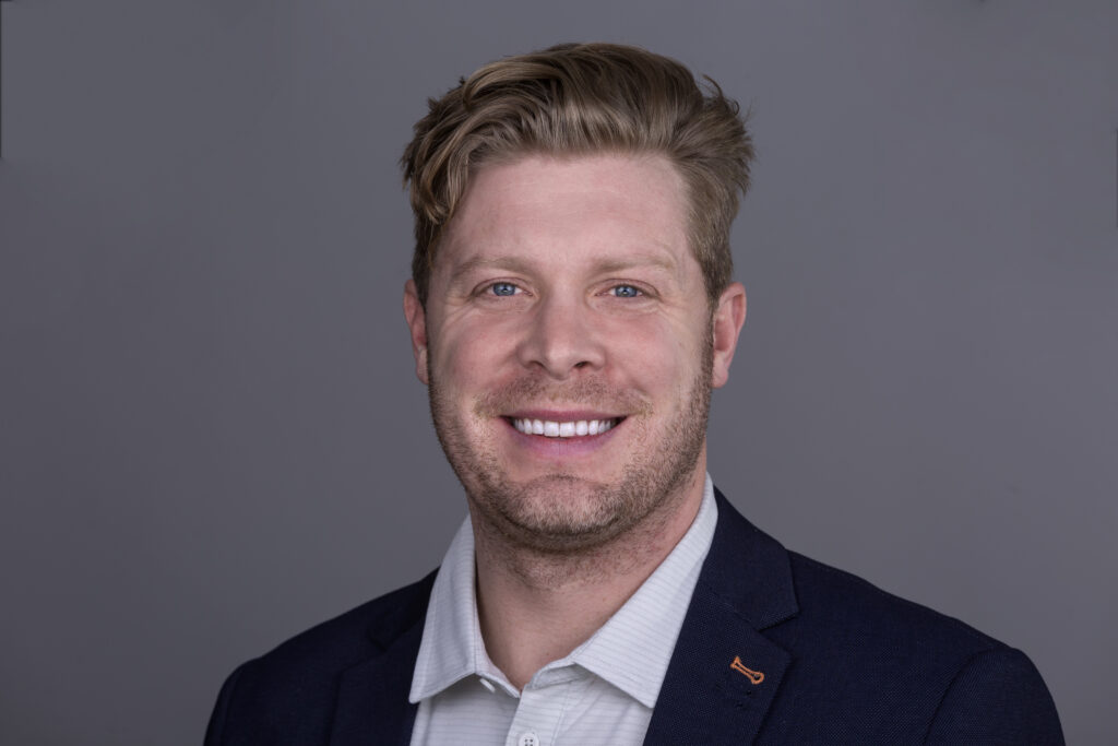 A man in a suit smiles for the camera.