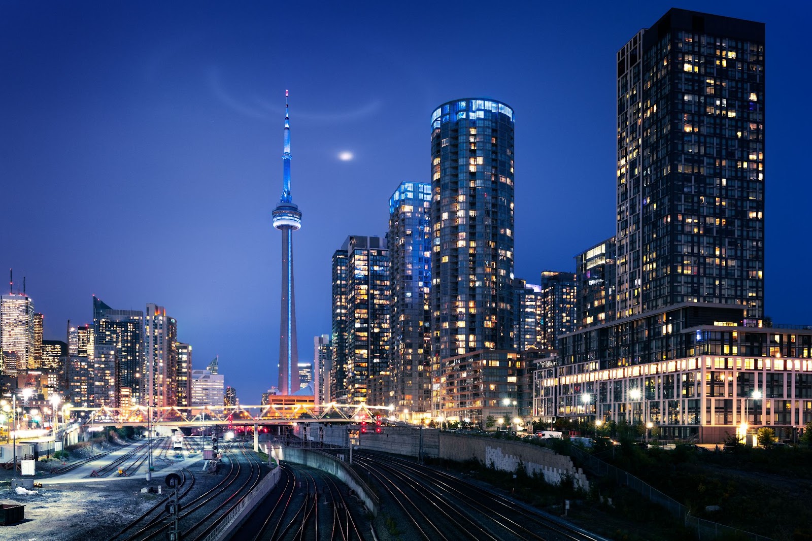 a city skyline with a tall tower and train tracks