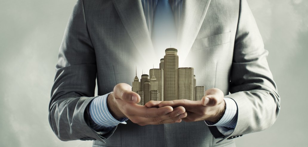 Real estate businessman holding a model of a city in his hands.