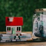 close-up view of glass jar with money, house model and rubles banknotes on wooden table