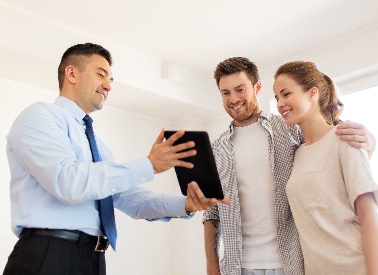 couple and realtor with tablet pc at new home