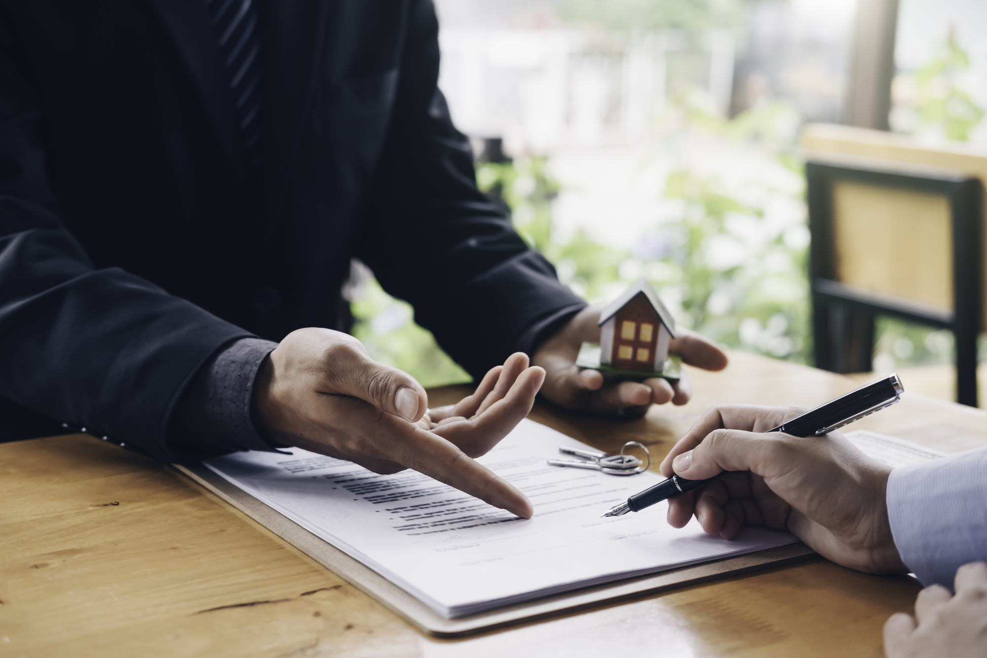 real estate agent holding house key to his client after signing