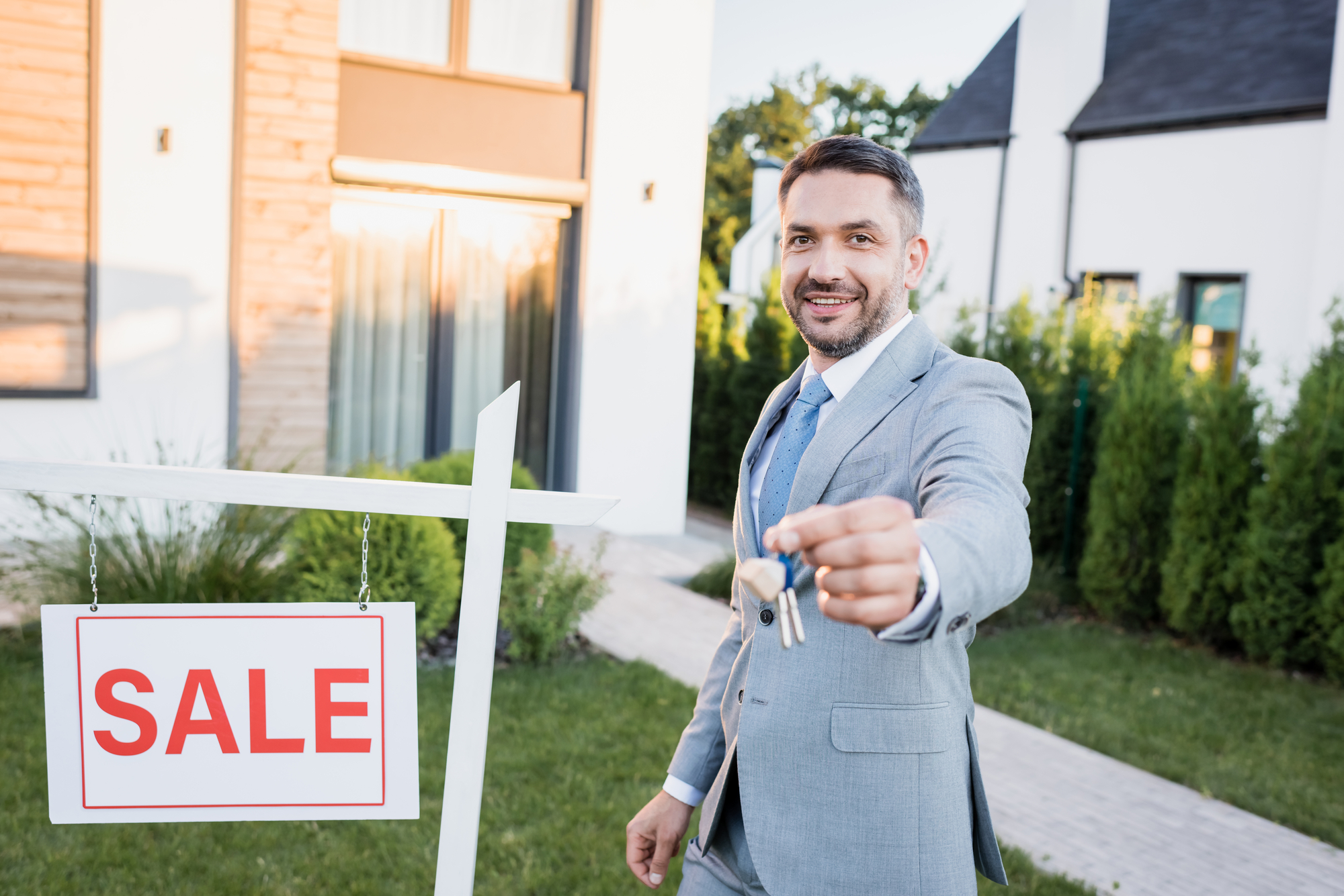 A man holding a sale sign in front of a house.