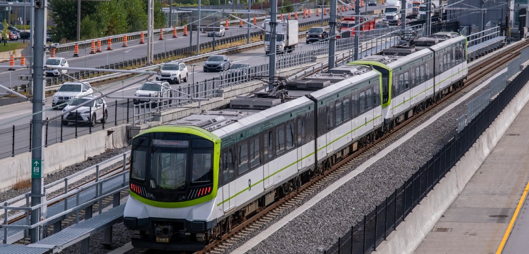 A green and white train traveling down the tracks.