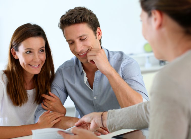 A man and woman are sitting at a table with a loan officer.