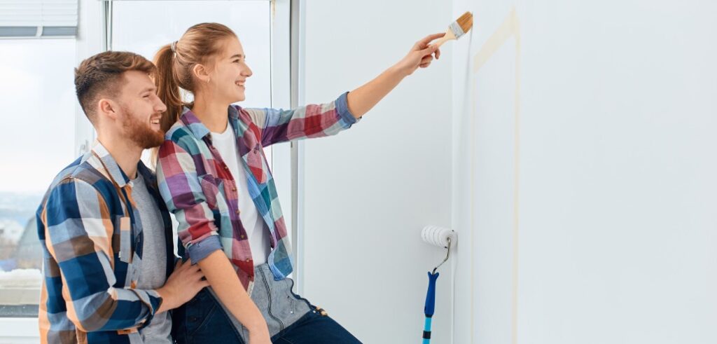 Young couple painting a wall in their home.