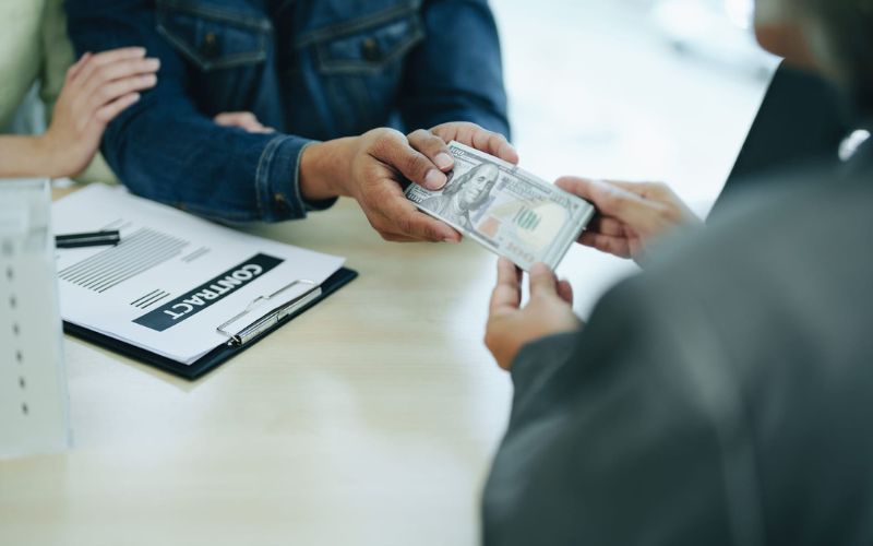 A man is handing money to a woman at a table.