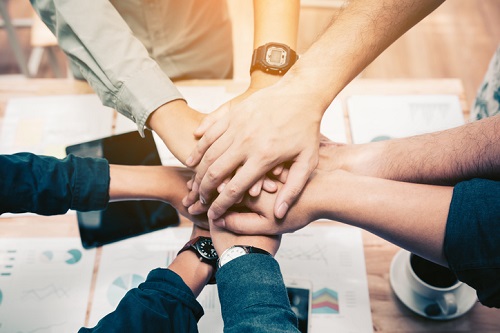 A group of people putting their hands together on a table.