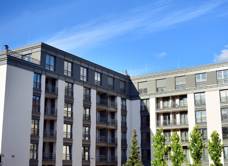 Modern residential buildings against a blue sky with scattered clouds.