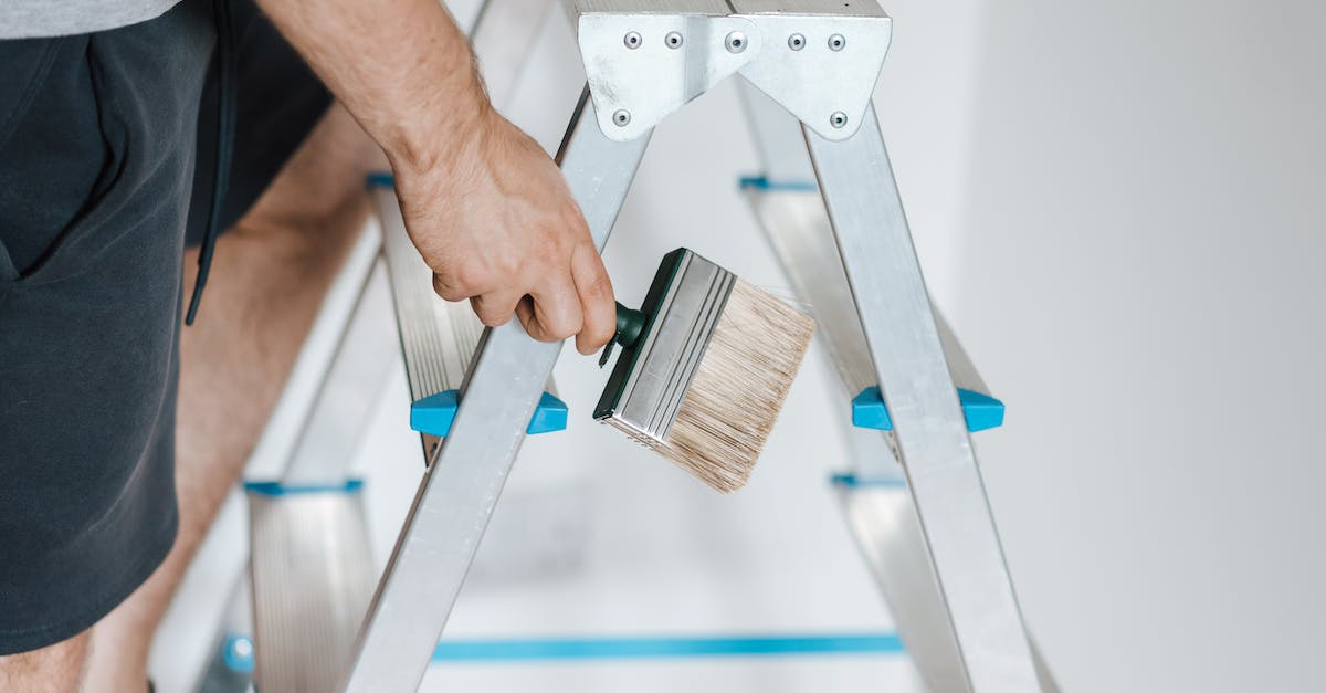 painter-with-brush-climbing-ladder-during-renovation-work