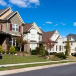 A row of suburban houses with well-manicured lawns in Calgary under a clear blue sky.