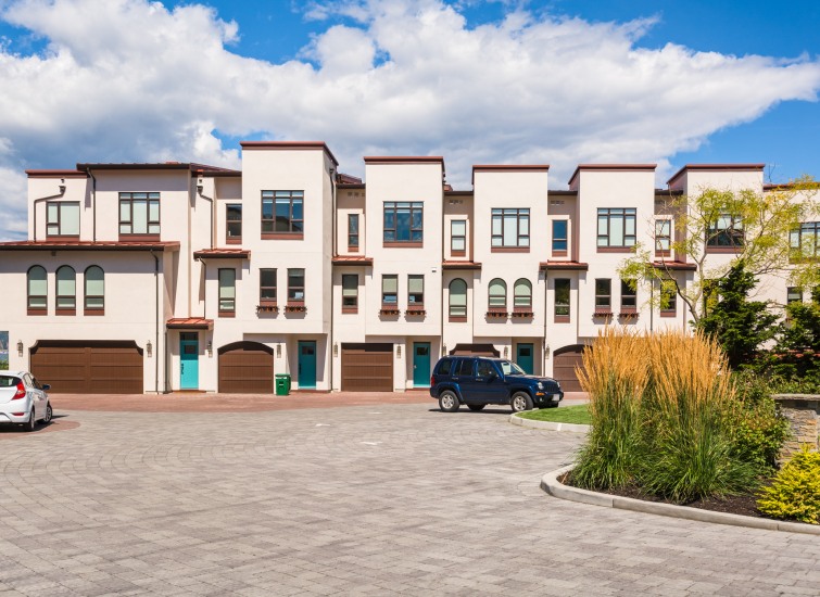 A row of townhouses with cars parked in front of them.